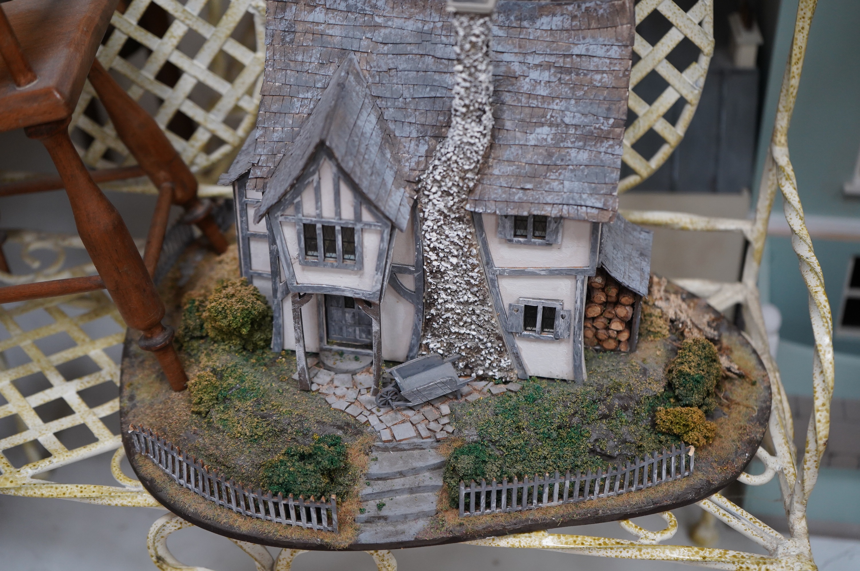A modern plywood slot together model of a chateau, 50cm high, together with six miniature doll’s houses, a miniature wrought iron garden bench and chair set, and three miniature wooden chairs. Condition - fair.